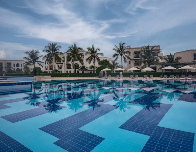 Rotana Salalah Pool with palm trees in the background.