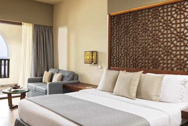 a double bedroom and a couch next to a terrace at fanar hotel residence hawana salalah oman