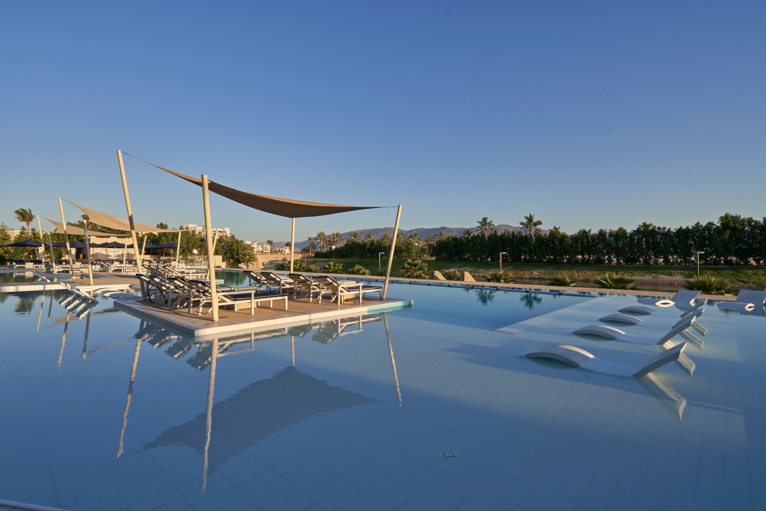pool area with seating decks and the mountains in the front view inside hawana salalah fanar hotel 