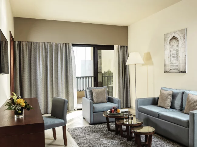seating area with a couch and a chair and a desk at the jaccuzi suite at fanar resort in hawana salalah oman