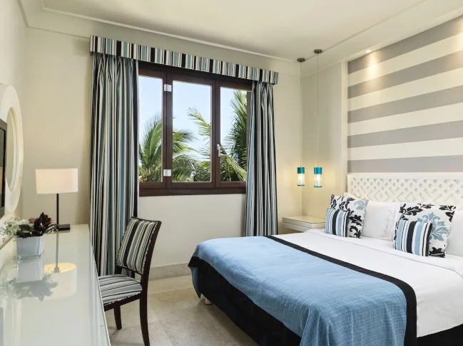 double bed and a chair by the window at the one bedroom apartment at fanar resort in hawana salalah oman