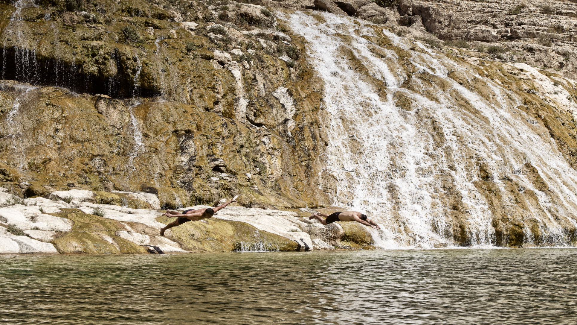 2 people swimming under the waterfalls excursion at wadi Derbat Oman