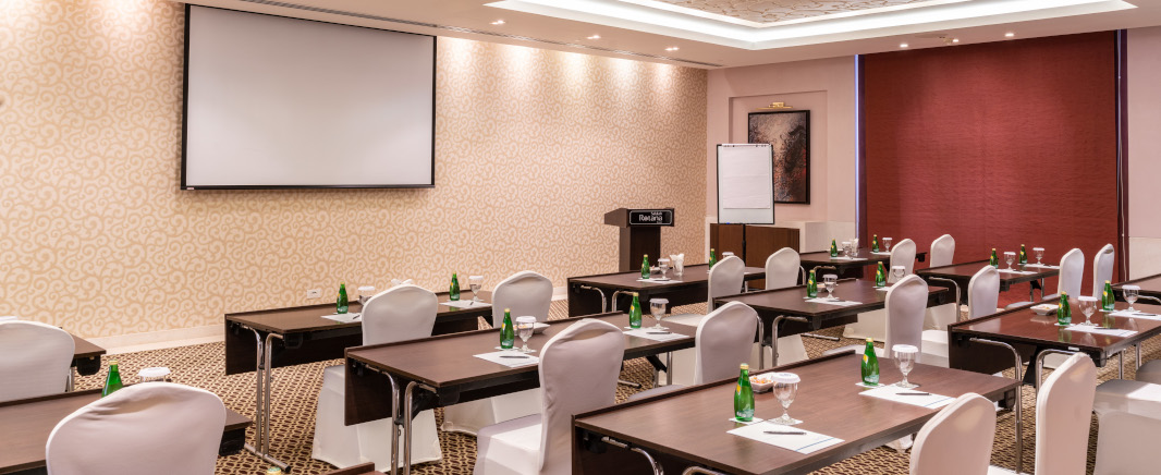 Rotana Salalah Meeting rooms with a brown tables and white chairs in front of white screen.