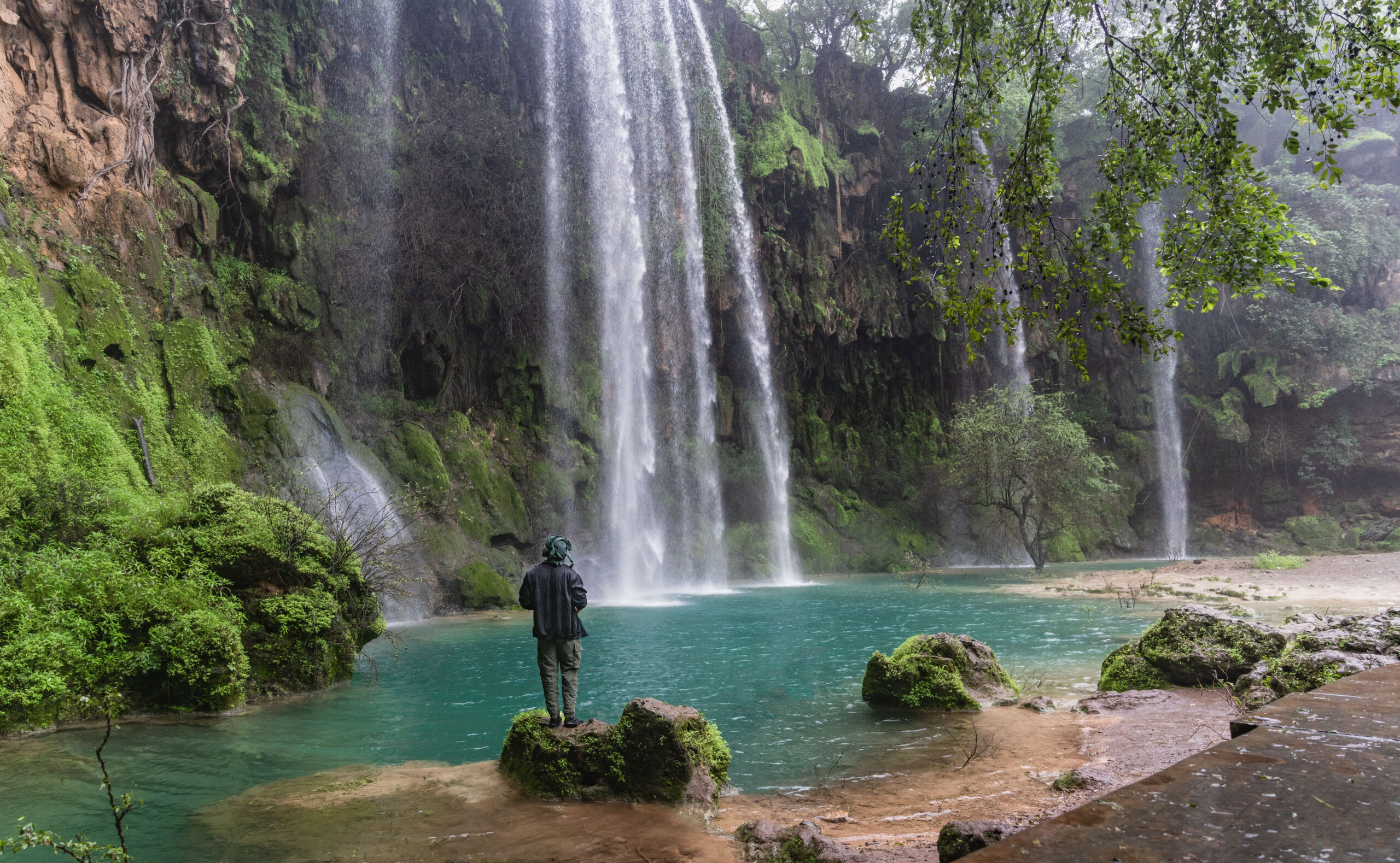 Waterfall flowing through a green valley in Dhofar during Khareef