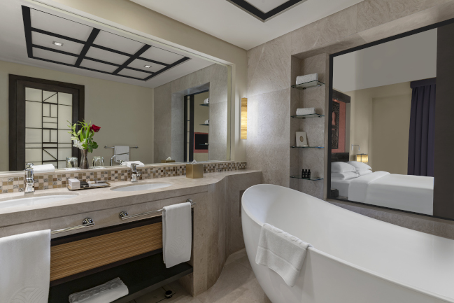 Two Bedroom suite bathroom with a marble sink and bathtub at Rotana Salalah Oman