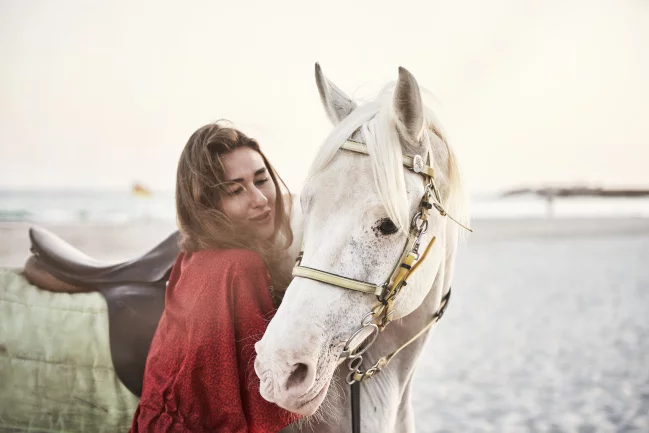 A girl petting on a horse in Salalah