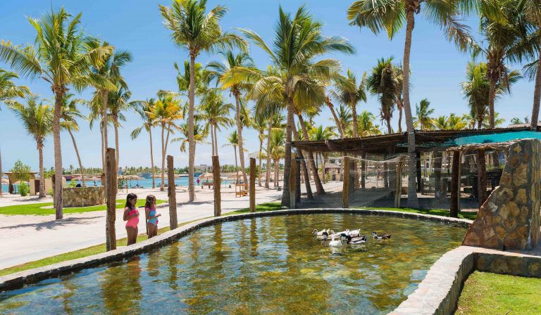 kids watching ducks swimming in an artificial lake at Hawana Salalah Oman.