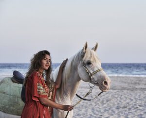 a women beside an Arabian white horse by the sea at Hawana Salalah Oman 