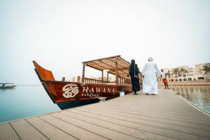 Arabic couple walking beside a boat in the Marina at hawana Salalah Oman.