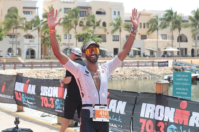 a ruuner raising his hands in a sign of celebrating a win at Ironman event at Hawana Salalah