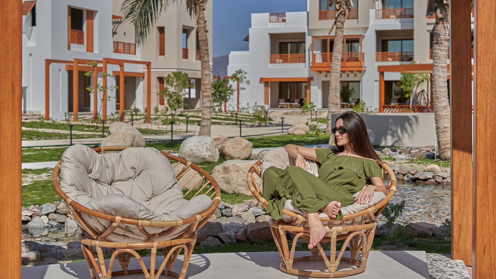 A girl sitting under the sun with the background of the buildings of the Club By Fanar Hotel Salalah