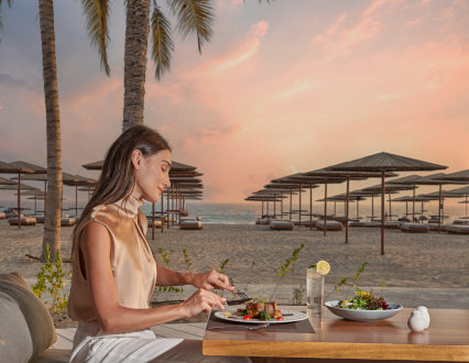A girl having dinner with a sea view at The Club By Fanar Hotel